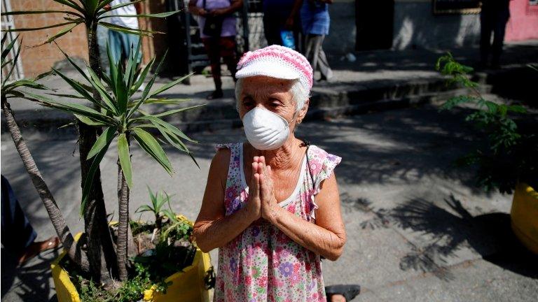 A woman on her knees while wearing a protective mask reacts as The Nazarene of St Paul procession passed-by despite a nationwide quarantine due to the coronavirus disease (COVID-19) outbreak in Caracas, Venezuela April 8, 2020.