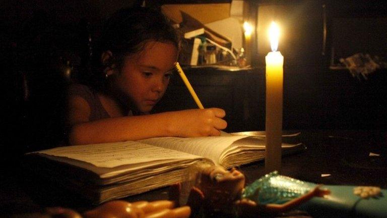 A girl does her homework by candlelight at his home during a power cut in San Cristobal, in the state of Tachira, Venezuela, 25 April 2016