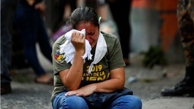 A relative reacts as police investigators collect evidence at a crime scene where a private securuty guard was purported killed by gang members, as the government undertakes steadily stricter measures to prevent the spread of the coronavirus disease (COVID-19), in San Martin, El Salvador April 26, 2020