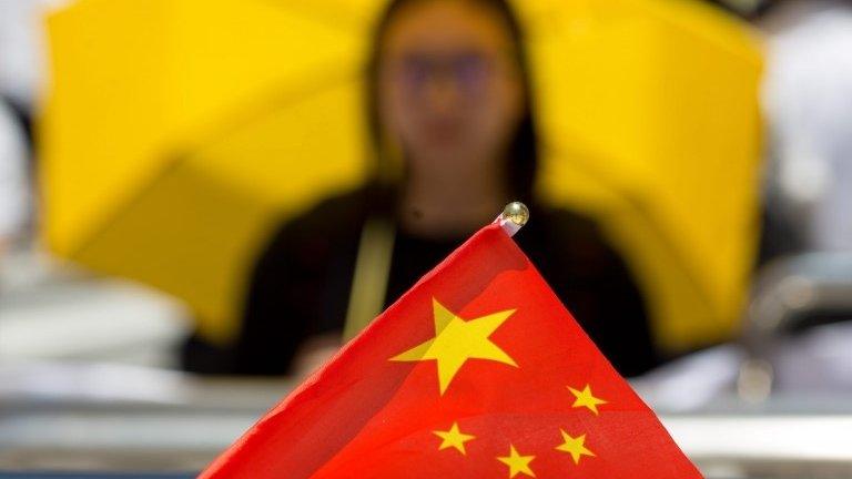 A yellow umbrella behind a Chinese flag