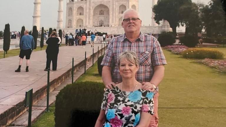 Ian Ball, standing outside the Taj Mahal, in India, with his arm son his wife, Jan Ball, whose sitting down