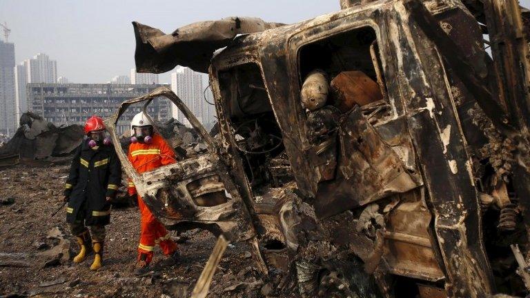 Firefighters walk near wreck of lorry in blast zone - 15 August