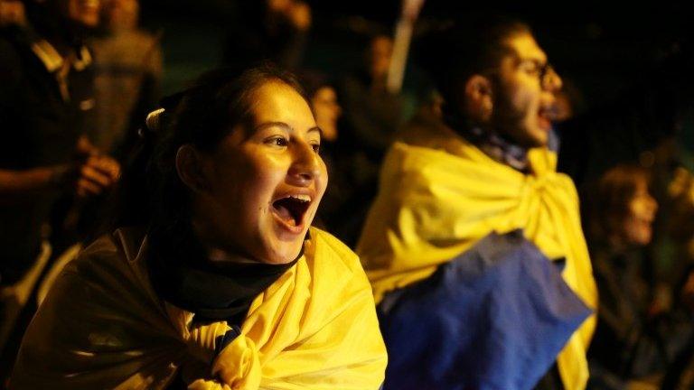 Demonstrators wrapped in Colombian national flags gather during a protest in Bogota on 27 November