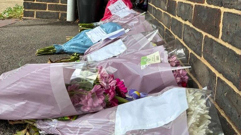 Bouquets of flowers left in front of the block of flats in tribute to the victim.
