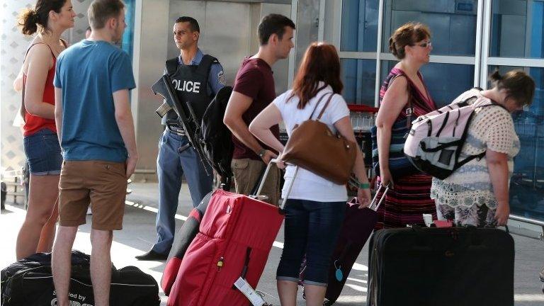 A Tunisian policeman stands guard (C) in front of British tourists at the Enfidha International airport