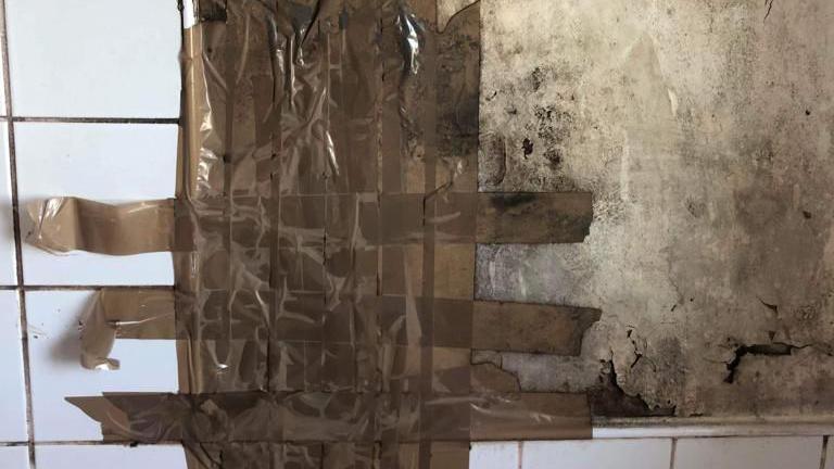 Mouldy bathroom wall taped over