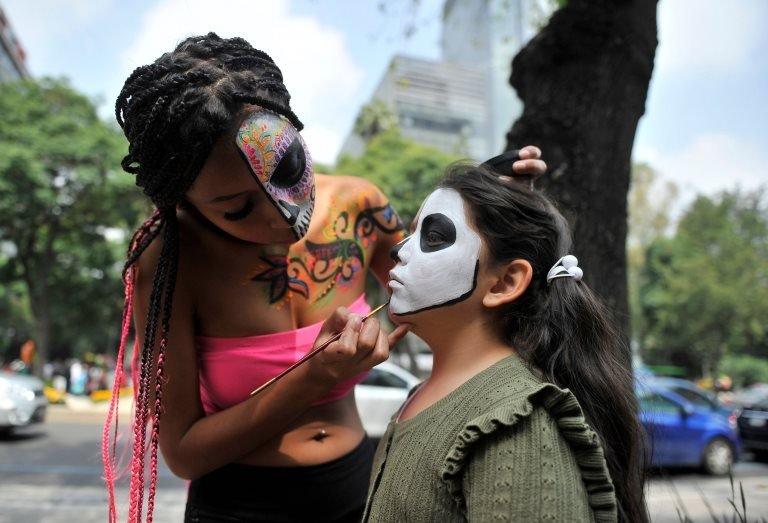 A girl is made up as Catrina during the "Catrinas Parade" along Reforma Avenue, in Mexico City on October 26, 2019