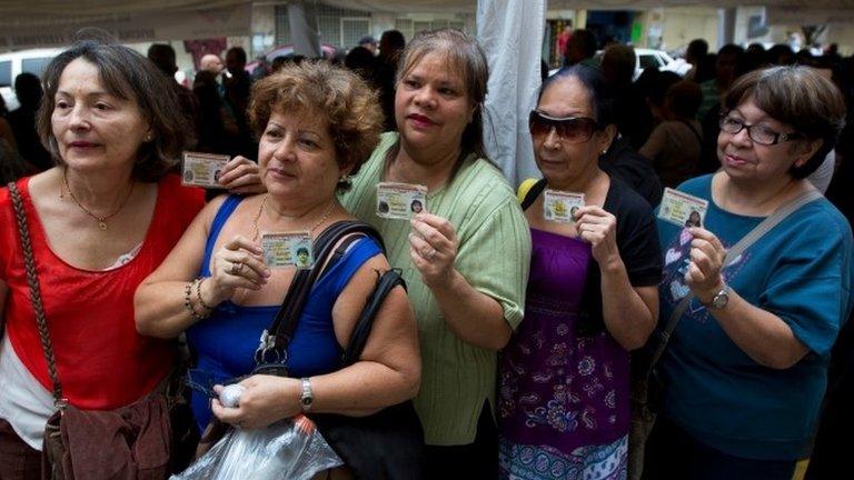 Women show their ID cards as they have their signatures checked in Caracas