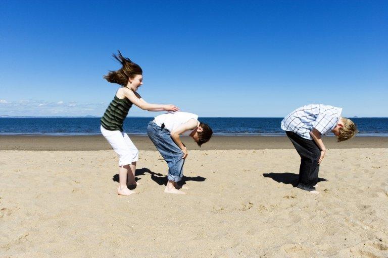 Children play leapfrog on the beach