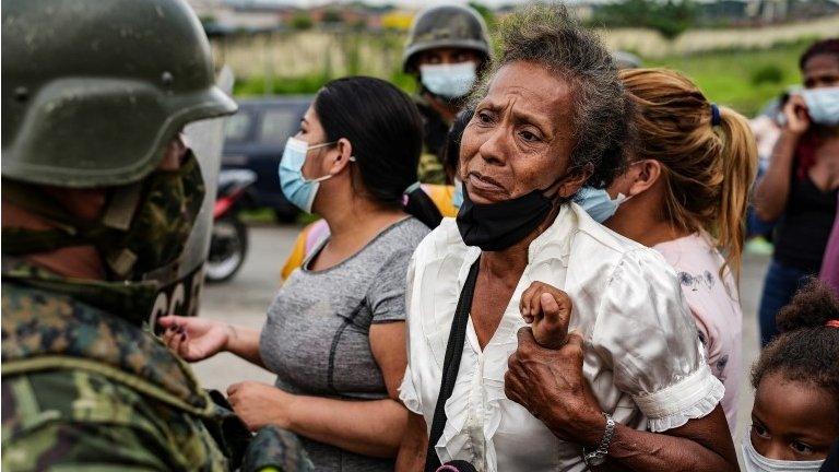 A woman holds on to a child while standing outside a prison where inmates were killed during a riot that the government described as a concerted action by criminal organisations, in Guayaquil, Ecuador February 23, 2021