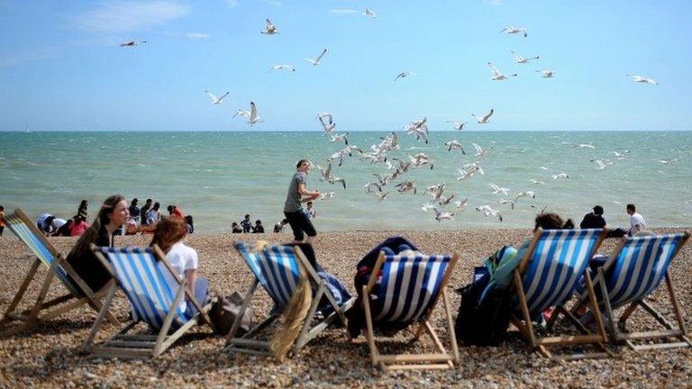 People in deck chairs on a beach