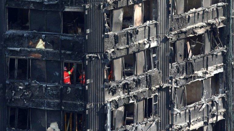 Members of the emergency services work inside burnt out remains of the Grenfell Tower