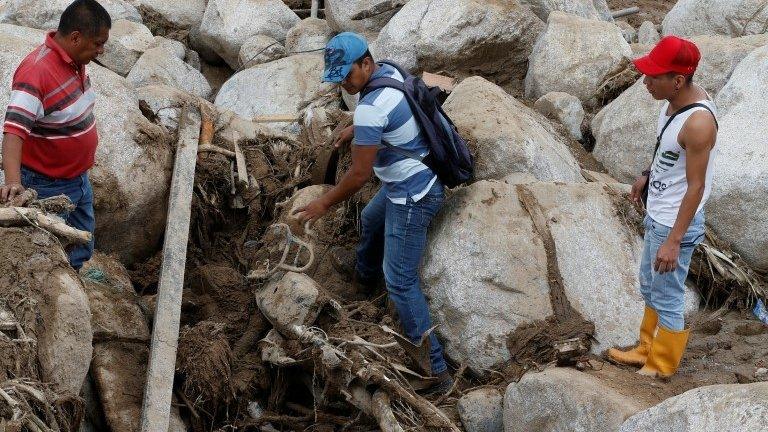 Men try to recover a motorcycle on a street destroyed after flooding and mudslides caused by heavy rains in Mocoa, Colombia April 2, 2017