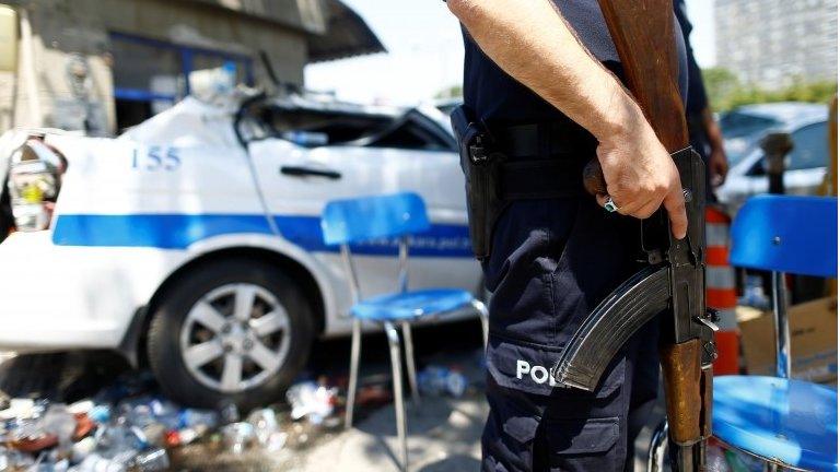 A police officer stands guard next to a damaged car at the entrance of the police headquarters in Ankara, Turkey (July 18, 2016)