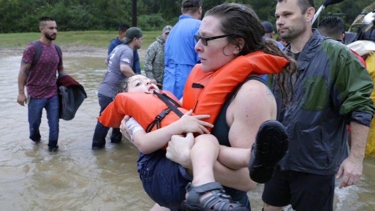 A woman and her son are helped out of a boat after being rescued from their home 15 miles north-west of downtown Houston, Texas, 28 August 2017