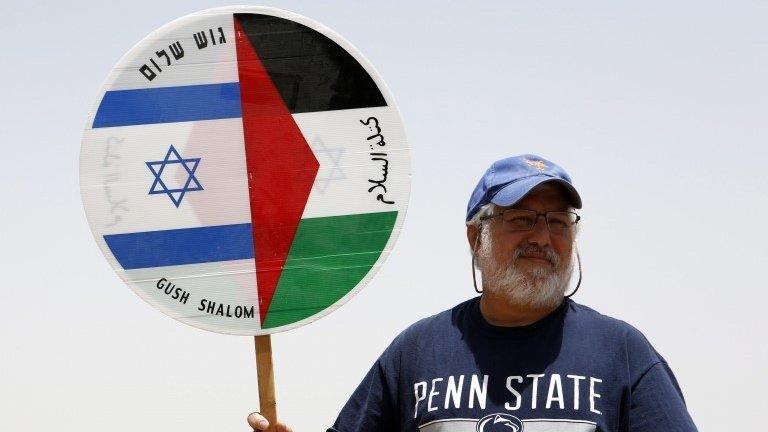 Israeli demonstrator holds placard during Israeli-Palestinian Freedom March in West Bank (03/06/16)