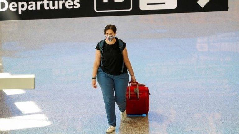 A passenger wearing a protective face mask walks at Fiumicino Airport