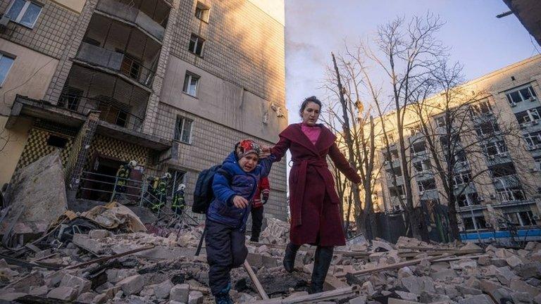 A Russian woman and child walk through debris in Kyiv