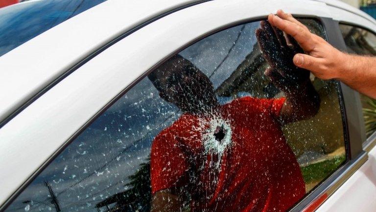 A man observes the broken window of his car, caused by a gunshot after gang attacks in Vitoria, Espirito Santo state, Brazil