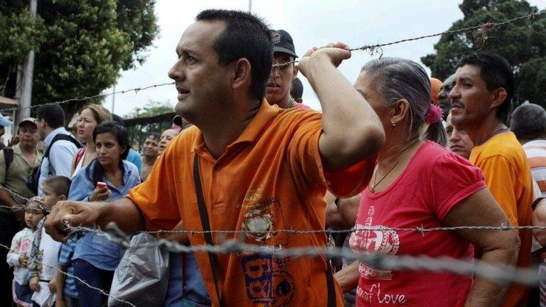 People stand next to barbed wire fences as they try to cross the border to Colombia over the Francisco de Paula Santander international bridge in Urena