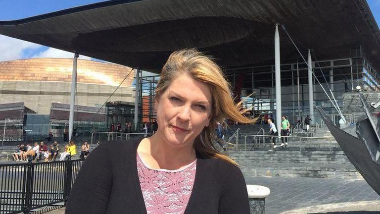 Rhianon Passmore standing in front of the Senedd building in sunshine