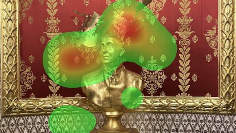 A gold statue of a male bust, in front of ornate red and gold wallpaper, with a green and red infrared heat map superimposed over the top.