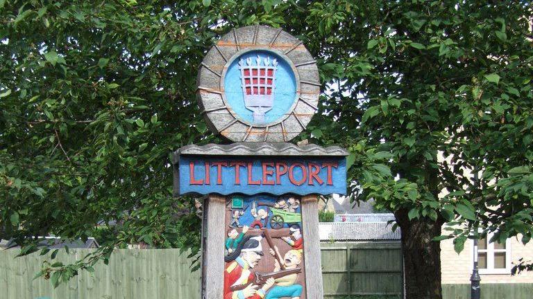 Littleport village sign with trees and a fence in the background