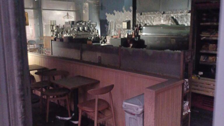 Inside smoke damaged coffee shop following a fire - coffee machine and serving area with table and chairs can bee seen blackened with smoke/fire.