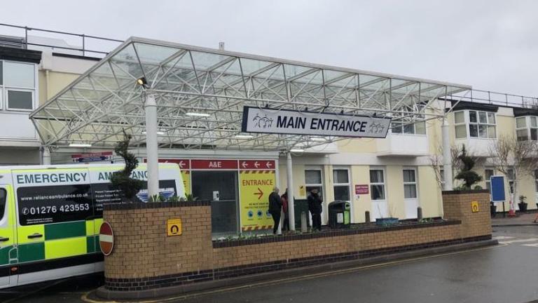 The main entrance to a hospital A&E department with an ambulance parked outside