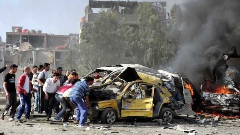 In this photo released by the Syrian official news agency Sana, flames and smoke rise from burning cars after two bombs exploded in Damascus, Syria