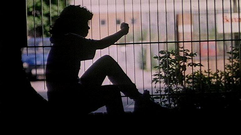 Silhouette of a girl looking through a park fence