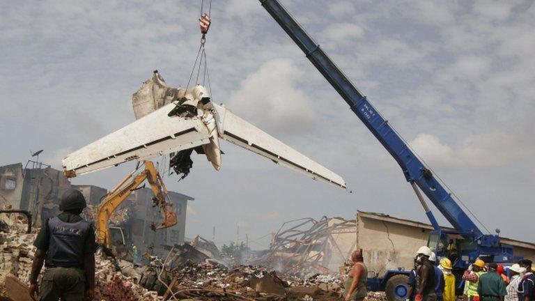 People watch as a crane lifts the tail of a plane after it crashed at Iju-Ishaga neighbourhood in Lagos 4 June 2012