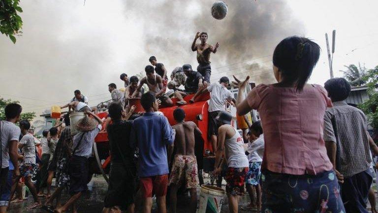 Ethnic Rakhine people get water from a firefighter truck to extinguish fire set to their houses during fighting between Buddhist Rakhine and Muslim Rohingya communities in Sittwe 10 June, 2012