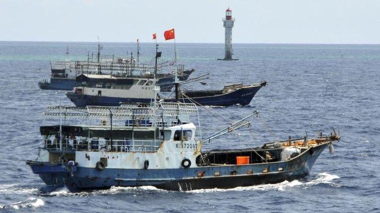 In this photo released by China's Xinhua, Chinese fishing vessels sail past a beacon of Zhubi Reef of the Spratly islands in South China Sea on 18 July, 2012