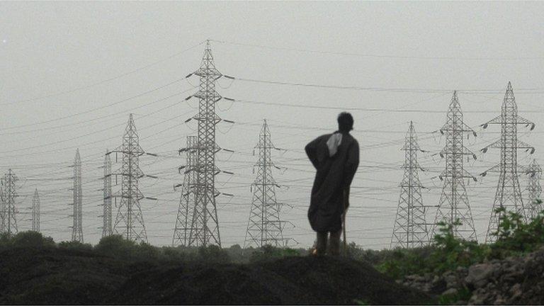 An Indian man looks at towers carrying electricity power cables in Mumbai on July 31, 2012.