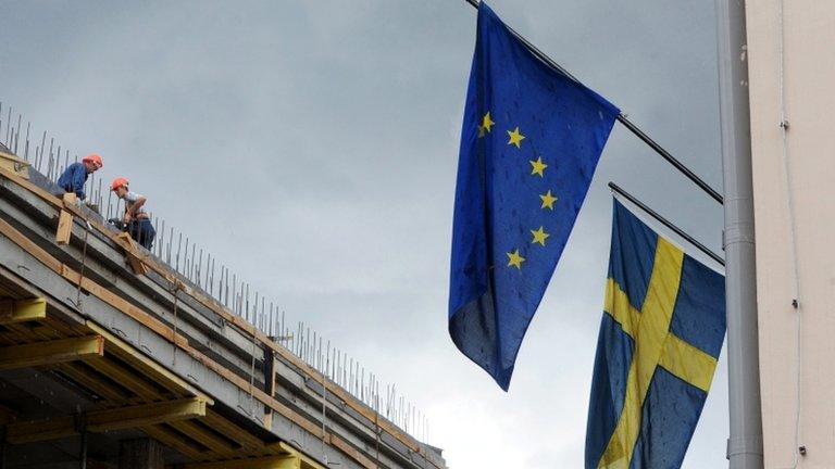 Men work atop a building which faces Sweden"s embassy building in Minsk