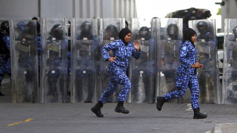 Two women riot police officers run in front of fellow officers standing as a barricade in Male, Maldives, 29 August 2012.