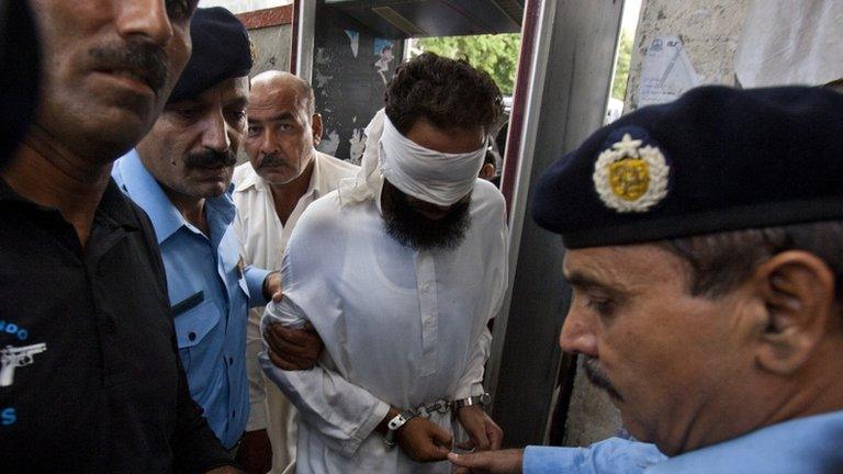 Pakistani police officers escort blindfolded Muslim cleric Khalid Chishti to appear in court in Islamabad