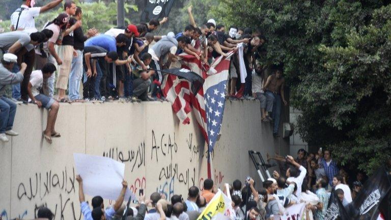 Protesters destroy an American flag pulled down from the US embassy in Cairo, Egypt, 11 Sept 2012