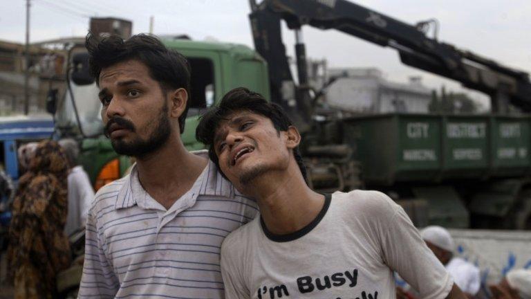 A Pakistani man comforts another at the site of the garment factory in Karachi, Pakistan, Wednesday 12 Sept 2012.