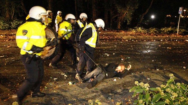 Dutch riot police stand next to a man lying on the ground in Haren, 21 September