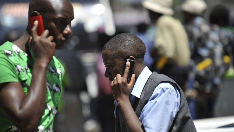 People walk while speaking on the phone on 1 October 2012 in Nairobi, Kenya