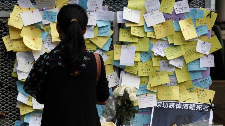 A girl stands in front of flowers and notes left by mourners for those who died in a ferry collision on Monday at a ferry pier in Hong Kong on 4 October 2012