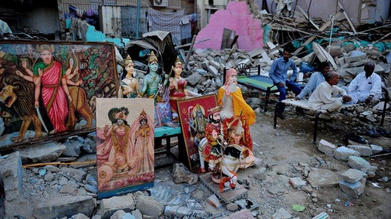 Pakistani Hindus sit next to a demolished Hindu temple in Karachi on December 2, 2012