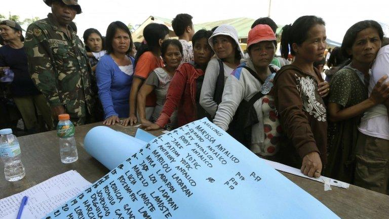 A list of missing people is prepared as residents line up for relief supplies in New Bataan on Thursday 6 December