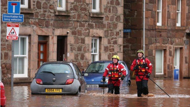 Firemen walk through floodwater on the High Street in Stonehaven