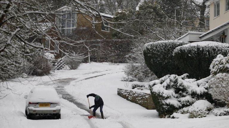 A man uses a snow shovel to clear snow from a road in Greenfield near Oldham, as wintry weather continues across the UK