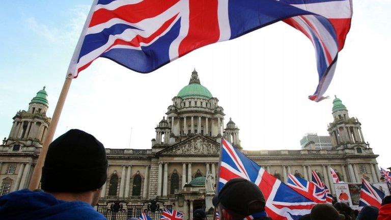 Loyalist protesters hold Union Flags during a demonstration outside Belfast City Hall