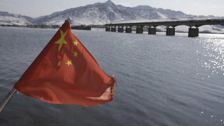 A Chinese flag is hoisted near the Hekou Bridge (R) linking China and North Korea, in Hekou, China, 7 February 2013