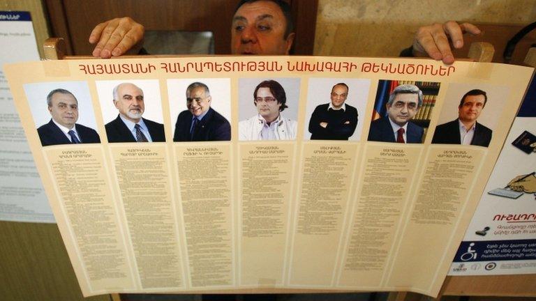 An election commission official puts up a poster with information about the candidates in Armenia's presidential election (17 February 2013)